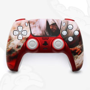 Puede incluir: Un mando PlayStation 5 DualSense rojo con una piel personalizada que presenta una figura encapuchada con una capa blanca. El mando tiene botones blancos y un logotipo de PlayStation blanco.