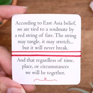 May include: A white card with red string and text about soulmates. The text reads, "According to East Asia belief, we are tied to a soulmate by a red string of fate. The string may tangle, it may stretch... but it will never break."