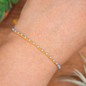 Pulsera o tobillera delicada de cuentas color mandarina y azul cielo, microtrenzada, ajustable, estilo minimalista.