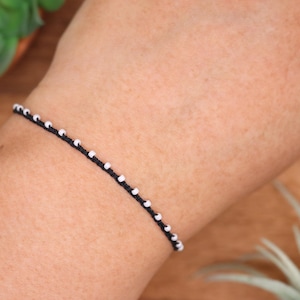 Schwarzes und elfenbeinfarbenes Perlenarmband oder -fußkettchen mit zartem Rocailles-Schliff, mikrogeflochten, verstellbar, minimalistisch