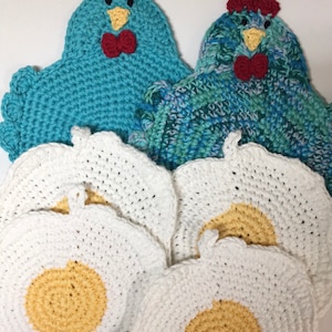 May include: Five crocheted white egg-shaped pot holders with yellow centers, and two crocheted blue chicken pot holders with red beaks and bows.