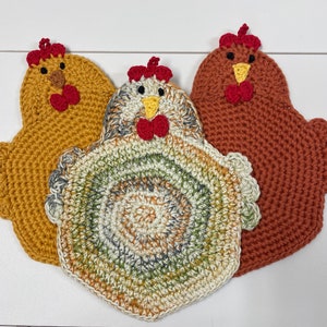 May include: Three handmade crochet chicken-shaped pot holders in shades of yellow, multicolored, and brown. Each has a red comb and wattle, and a yellow beak. The pot holders are designed with a scalloped edge and are suitable for kitchen use.