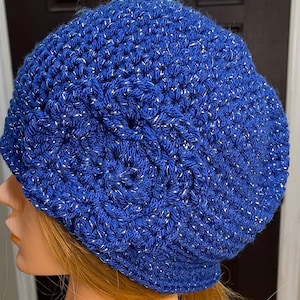 May include: A blue crocheted beanie with silver glitter thread. The beanie has a slouchy fit and a folded brim.
