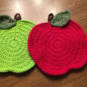May include: Two crocheted apple pot holders, one green and one red, with green crocheted leaves.