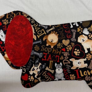 May include: A dog-shaped fabric item with a black background, featuring various dog illustrations, paw prints, hearts, and the words "I Love Dog" and "Love My Dog." It has a large red ear.