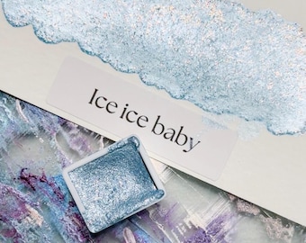 May include: A small, square pan of light blue metallic watercolor paint with the words "Ice Ice Baby" written on a white label.