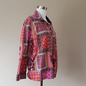 May include: A long-sleeved button-up shirt with a patchwork design featuring pink, orange, and black geometric patterns.