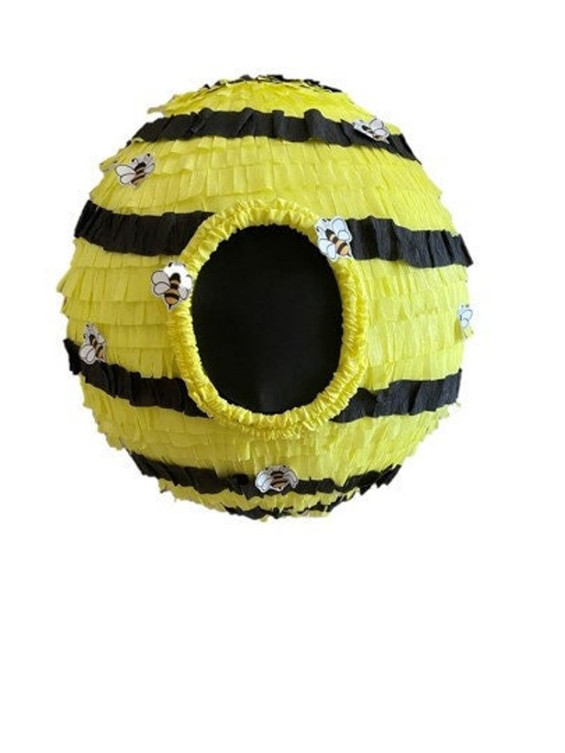 May include: A spherical pi&ntilde;ata in the shape of a beehive. The pi&ntilde;ata is yellow with black stripes and a large circular opening. Small bee stickers are placed around the pi&ntilde;ata. The pi&ntilde;ata is designed for a party or celebration.