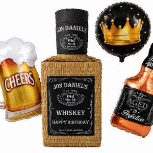 K&ouml;nnte beinhalten: Ein Set aus Partydekorationen mit einer beigefarbenen, rechteckigen Pi&ntilde;ata in Form einer Whiskeyflasche mit der Aufschrift Jon Daniel's Old No. 38 Brand Whiskey Happy Birthday, einem Bierkrug-Ballon mit Cheers, einem Kronen-Ballon und einem Flaschen-Ballon.