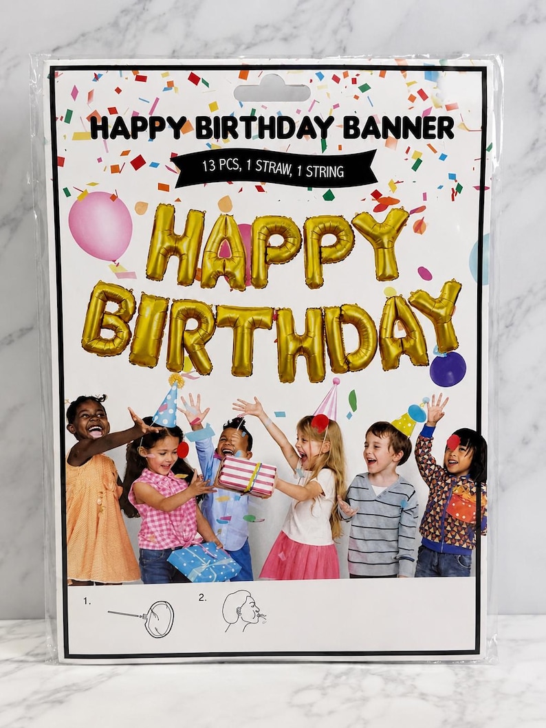 May include: A Happy Birthday banner kit in a plastic package containing 13 gold foil letter balloons, one straw, and one string. The packaging features text reading HAPPY BIRTHDAY BANNER, 13 PCS, 1 STRAW, 1 STRING, and an image of children.