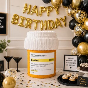 May include: A large orange and white cylindrical pi&ntilde;ata designed to resemble a prescription pill bottle with the text Old Farts Pharmacy, Fukitol 100mg, and instructions to take a handful whenever feeling irritable, grouchy, or just plain old.