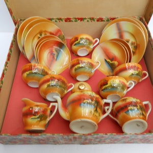 May include: A vintage porcelain tea set in a box. The set includes a teapot, creamer, sugar bowl, four teacups, and four saucers. The porcelain is decorated with a colorful floral pattern.