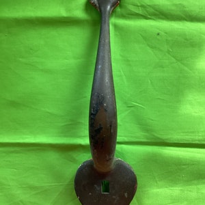 May include: A dark brown metal door handle with a heart-shaped base and a pointed top. The handle has a small square hole in the center.