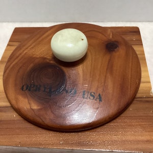 May include: A wooden box with a lid. The lid has a white knob and the words "OPRYLAND USA" printed on it.