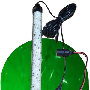 May include: A white LED light strip with a black housing and a 12V cigarette lighter plug. The light strip is connected to a pair of red and black alligator clips. The light strip is illuminating a green surface.