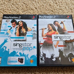 May include: Two PlayStation 2 game cases for SingStar Pop and SingStar Rocks. Both cases feature images of people singing into microphones. The SingStar Pop case is blue and white, while the SingStar Rocks case is black and red.