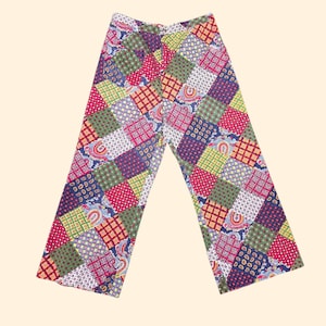 May include: Wide-leg trousers featuring a vibrant patchwork design composed of various square fabric panels. The pattern includes a mix of paisley, polka dot, and grid motifs in shades of red, green, blue, yellow, and white throughout the garment.