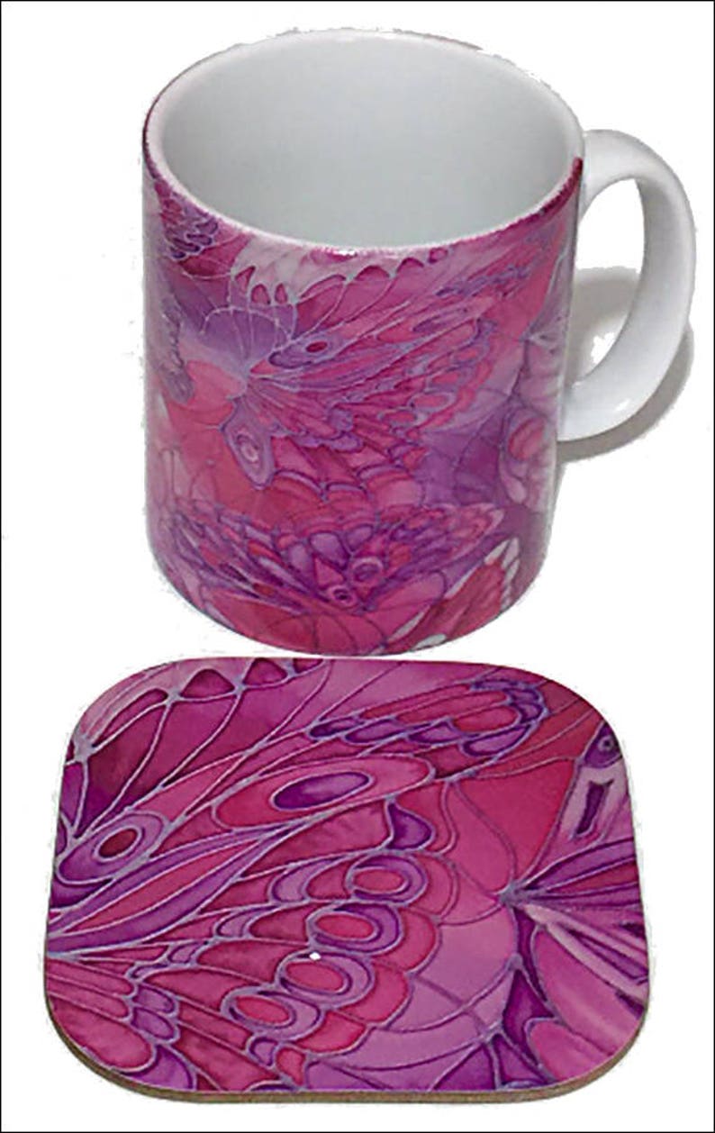 K&ouml;nnte beinhalten: Eine rosa und lila Keramiktasse mit einem Schmetterlingsdesign. Die Tasse wird mit einem passenden Untersetzer geliefert.