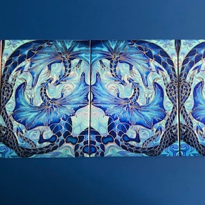 May include: An abstract art print in blue and white featuring a pair of stylised dragons with intricate details. The dragons are facing each other with their wings spread out.