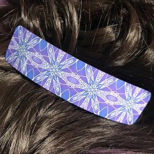 May include: Purple and blue patterned hair clip with a geometric design.