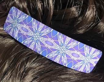 Op de afbeelding: Paarse en blauwe haarspeld met een geometrisch ontwerp.