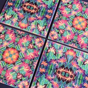 May include: Four square ceramic tiles featuring a repeating pattern of colourful flowers and leaves. The tiles are painted in shades of pink, purple, blue, green, and yellow.