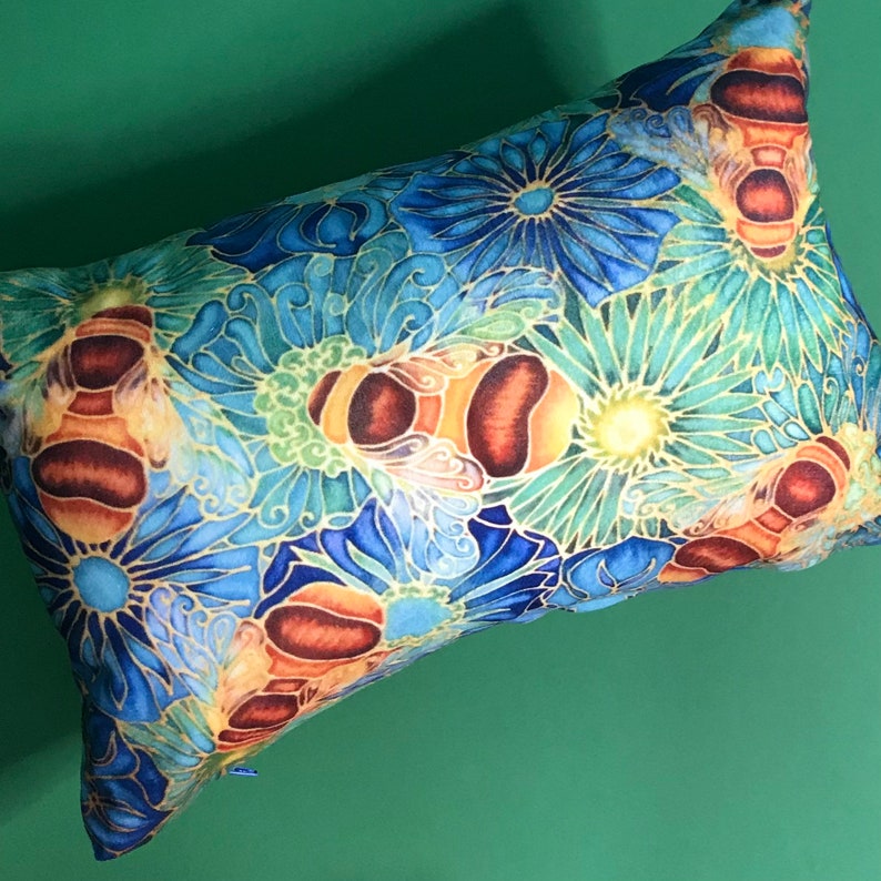 May include: A decorative pillow with a floral pattern featuring bees and flowers in shades of blue, green, and yellow.