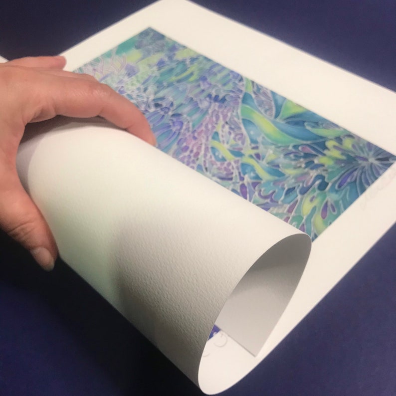 May include: A white mat with a rolled up print of a colorful abstract design. The print is a watercolor painting with shades of blue, green, purple, and yellow.
