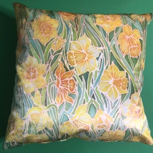 May include: A decorative pillow with a floral pattern featuring yellow daffodils on a green background.