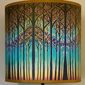 May include: A lampshade featuring a colourful forest scene. The trees are silhouetted against a gradient background of blue, purple and yellow.