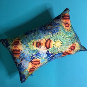 May include: A blue and gold pillow with a floral pattern and bee designs. The pillow is made of soft fabric and has a zipper closure.