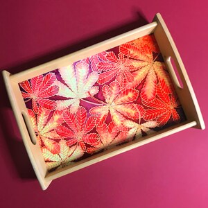 May include: A wooden serving tray with a red and yellow leaf design. The tray has two handles on the sides.