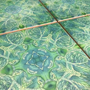 May include: Green and blue patterned ceramic tiles with a repeating design of stylised leaves and flowers. The tiles have a glossy finish.