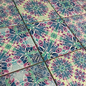 May include: A set of six decorative tiles featuring a repeating pattern of blue, green and purple butterfly wings. The tiles are made from ceramic and have a glossy finish.