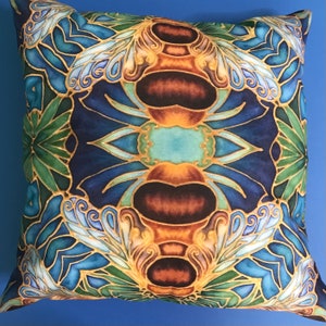 May include: A decorative cushion with a blue, green and gold geometric pattern featuring a stylised bee design.