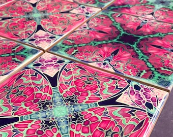 May include: Set of six square ceramic coasters with a pink, green, and blue geometric pattern. The coasters feature a repeating design of stylized butterflies.