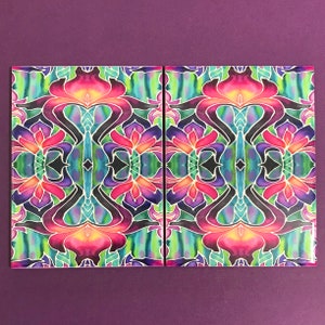 Könnte beinhalten: Zwei farbige quadratische Fliesen mit einem symmetrischen Muster aus rosa, lila, blauen, grünen und gelben Blumen. Die Fliesen sind aus Keramik und haben eine glänzende Oberfläche.
