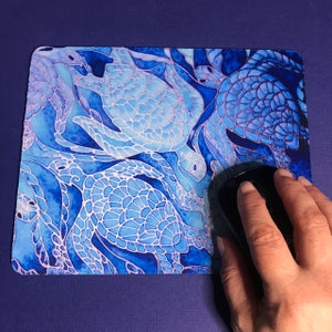 May include: A blue and white mouse mat featuring a design of sea turtles. The turtles are outlined in white and have a blue and white patterned shell.