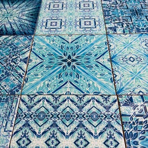 May include: A collection of blue and white patterned ceramic tiles with intricate geometric designs. The tiles feature a variety of patterns, including floral, geometric, and abstract designs.