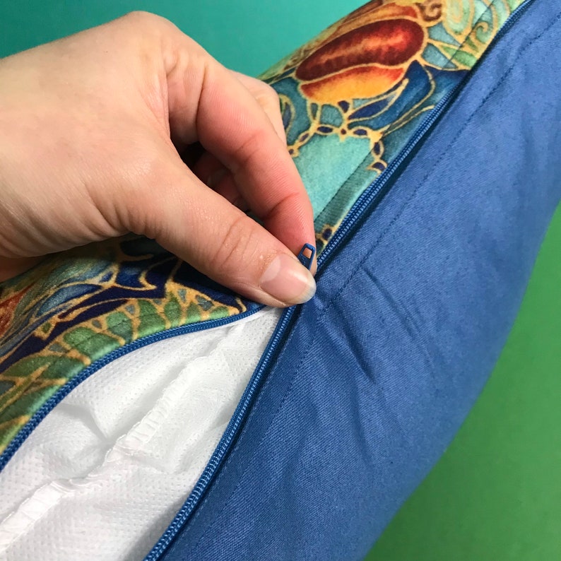 May include: A blue pillow cover with a zipper closure. The cover has a colorful floral pattern with gold accents.