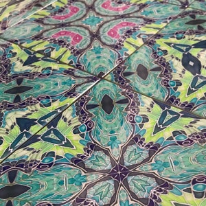 May include: A close-up of a patterned tile with a kaleidoscope design in shades of green, blue, black, and pink.