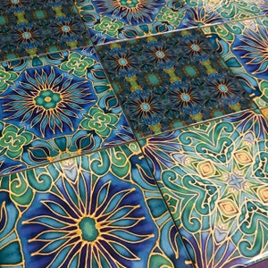 May include: A set of decorative ceramic tiles featuring a blue, green and gold geometric pattern. The tiles have intricate floral designs and a mandala-like motif.