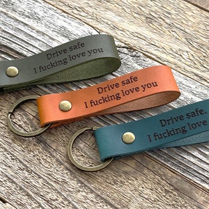 May include: Three leather keychains with metal rings. Each keychain has a different color: green, brown, and blue. The keychains are engraved with the text "Drive safe, I fucking love you".
