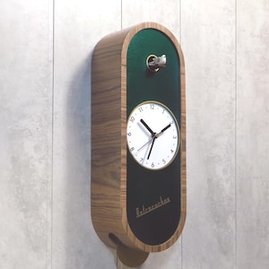 May include: A green and wood cuckoo clock with a white face and black hands. The clock has a small bird on top and the text "Retrocuckoo" on the bottom.