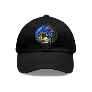 May include: Black baseball cap featuring a circular patch with a stylized wolf design in blue, yellow, and gray, with the word "EYEBLAD" in white. The cap has a curved brim and a classic, adjustable fit.