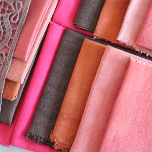 Peut inclure: Un assortiment d'échantillons de tissu dans différentes nuances de rose, orange et marron. Le tissu est disposé en quinconce, la couche supérieure étant ornée d'une délicate dentelle.