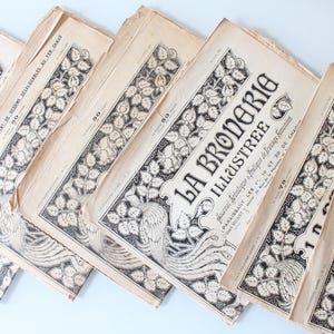 Peut inclure: Plusieurs magazines français anciens, "La Broderie Illustrée", sont présentés. Les couvertures présentent des illustrations florales et d'oiseaux en noir et blanc. Le papier vieilli montre des signes d'usure, indiquant leur statut vintage.