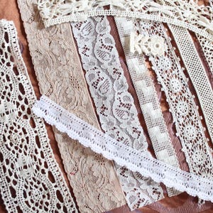 May include: Assortment of white and cream lace trim, featuring various patterns and widths. The lace is delicate and intricate, with a variety of textures and designs.