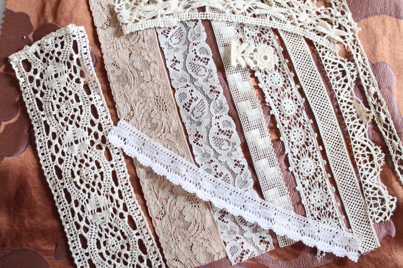 May include: Assortment of white and cream lace trim, featuring various patterns and widths. The lace is delicate and intricate, with a variety of textures and designs.