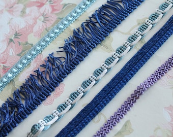 May include: Assortment of blue and white trim with different textures and patterns. The trim includes a beaded trim, a fringed trim, a braided trim, and a woven trim.